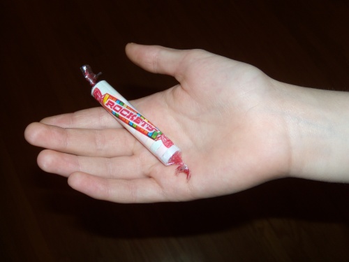 A hand holding out a piece of Halloween candy